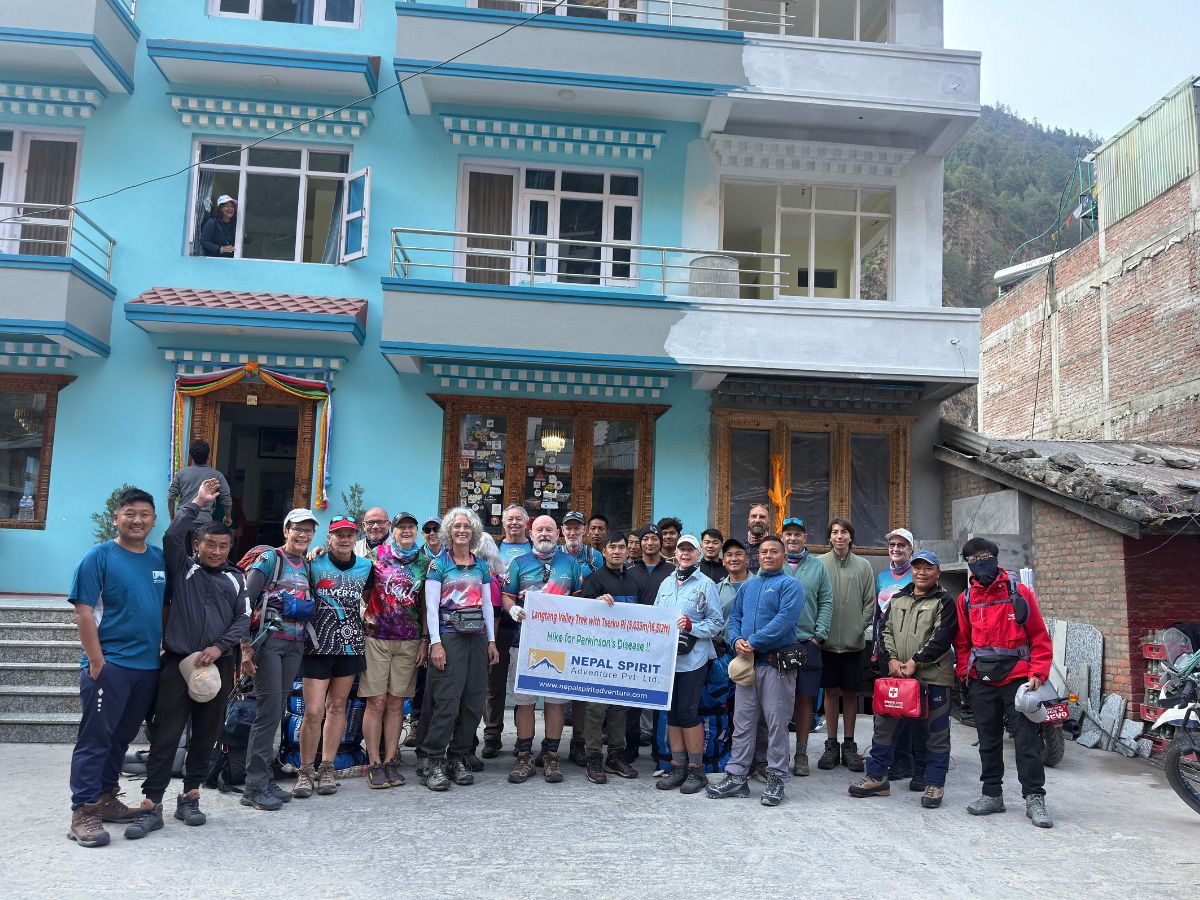 A team of trekkers smiling for a group photo in Syabrubesi, Nepal.